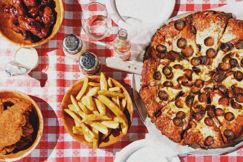 A table spread of pizzas, fries, and wings